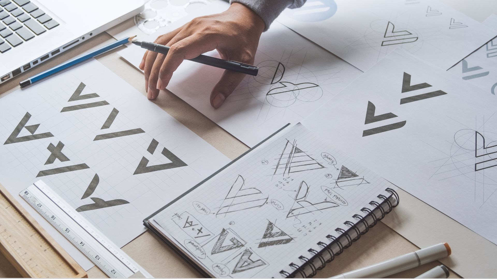 A person diligently working on a design, using a pen and paper to bring their creative ideas to life.